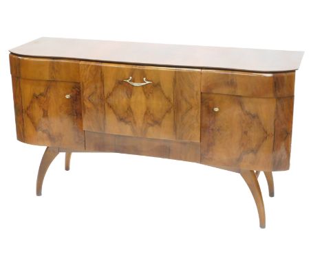 A 1950s walnut sideboard, the shaped top above an arrangement of two drawers, and two doors flanking a pull down cocktail are