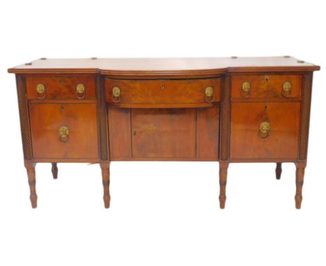 A George IV mahogany breakfront sideboard, the top with cylindrical brass rail, the base with an arrangement of three drawers