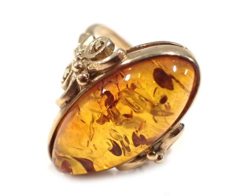 A 9ct gold and amber dress ring, the oval amber in rub over setting, with scroll shoulders, ring size M½, 5.2g all in, boxed.