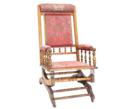 A late 19thC American walnut rocking chair, with a padded back, arm rest and seat, with turned stretchers, and ceramic castor