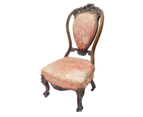 A Victorian mahogany nursing chair, the shield shaped back carved with leaves and flowers, with a padded serpentine fronted s