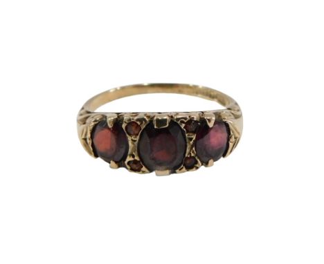 A 9ct gold garnet dress ring, set with three oval garnets and four round brilliant cut garnets, in gypsy setting, with scroll