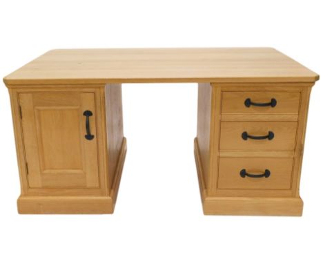 A light oak partner's kneehole desk, rectangular top with canted corners above an arrangement of false drawers and drawers to