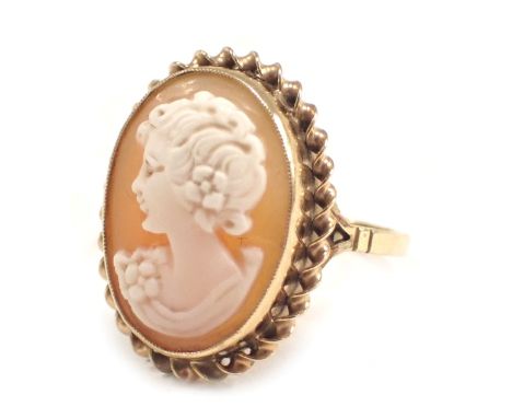 A 9ct gold shell cameo dress ring, the oval cameo depicting a figure looking dexter, in an oval rub over setting with rope tw