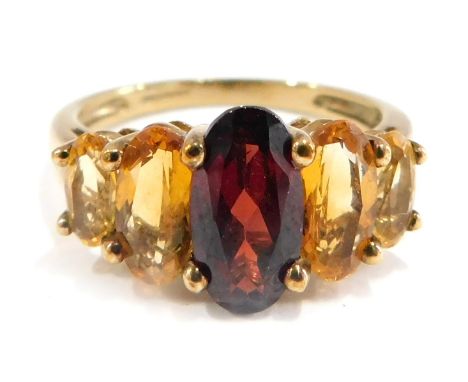 A 9ct gold multi stone dress ring, set with garnet, citrine and topaz, each oval cut, in a raised claw setting, on a plain ba