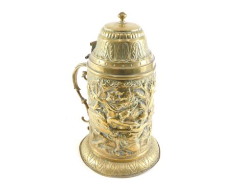 A 19thC continental embossed brass lidded tankard, decorated with figures boar hunting, and a scroll handle, 33cm high. 