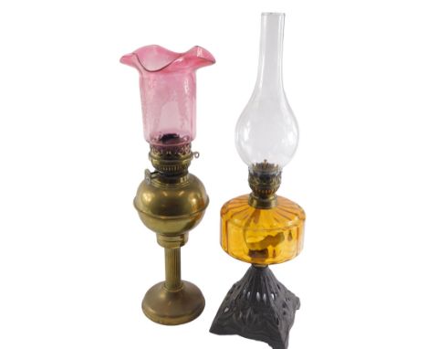 A Victorian oil lamp, with an amber tinted reservoir and a cast iron base, 57cm high, and a brass oil lamp with cranberry tin