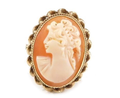 A 9ct gold cameo dress ring, the oval cameo set with maiden looking dexter, in a rub over border with twist shoulders, on V s