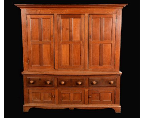 An early Victorian oak housekeeper's cupboard, moulded outswept cornice above a pair of panelled doors flanking a central sec