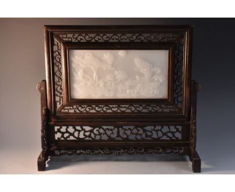 A Chinese pale jade and hardwood table screen, the rectangular panel carved in high relief with a lakeside scenes of carp spr