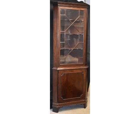 A George III Revival mahogany floor-standing splay-fronted corner display cabinet, stepped cornice above an astragal glazed d