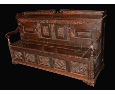 A '17th century' oak box settle, three-quarter gallery above a pair of panelled doors, hinged seat, the front carved with loz