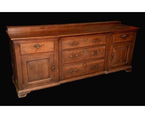 A George III oak low dresser, moulded top above an inverted break-centre arrangement of five drawers and a pair of raised and