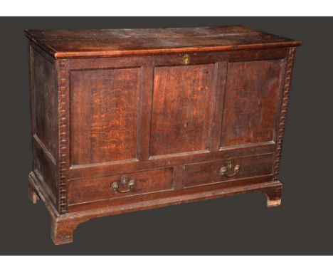 A George III oak mule chest, hinged top, three panel front flanked by architectural rusticated angles, above a pair of cockbe