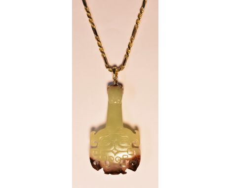 A Chinese carved pendant necklace, green and brown banded jade shaped panel carved as a totem mask head beneath a serpent hea