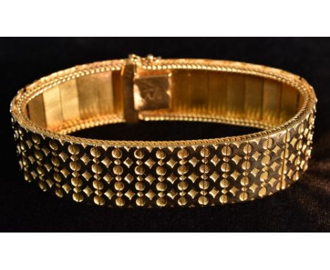 An 18ct gold articulated panel bracelet, relief cast with interconnected rings above a scaled ground, united by a compression