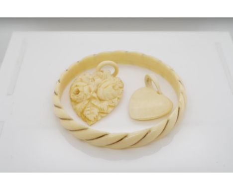 A collection of vintage carved ivory jewellery includes two carved heart pendants and a twist bangle. These items may not be 