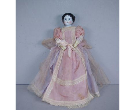 Antique ceramic head doll in original dress, including underwear and velvet shoes, fabric body and limbs. Circa 1880. Height 