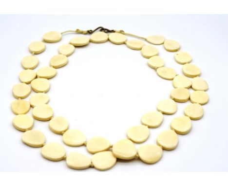 An opera length ivory necklace with flat sectional beads on double knotted string. This item may not be exported.