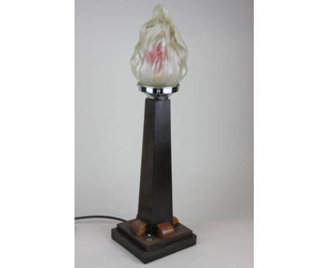 An Art Deco table lamp, the square tapered wooden base below a glass shade modelled as a flame