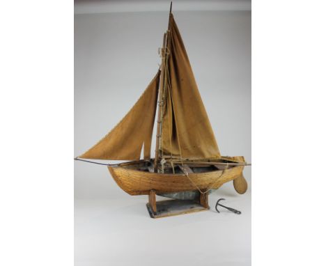 A wooden model of a sailing boat with two sails, a rudder and an anchor 83cm high