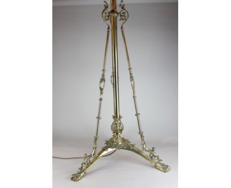 A brass adjustable standard lamp with highly decorated tripod base on hairy paw feet, 155cm high