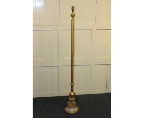 A gilt metal oval wall mirror with scroll and floral border and cartouche, together with a gilt metal standard lamp with dolp