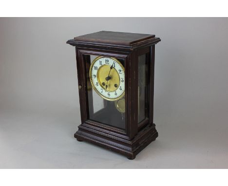 A mahogany and glass cased mantel clock with circular white enamel and brass dial with Arabic numerals, 30cm high