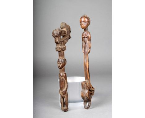 Two Baule gong beaters, Ivory Coast; both with carved standing female figures and masks, with bound cloth, 28.5cm and 31cm hi