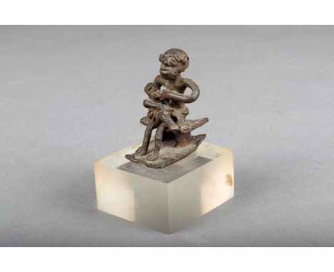 An Ashanti brass gold weight, mother and child on a stool, 4.7cm high, on a perspex base. Provenance Gimpel Fils Ltd, London,