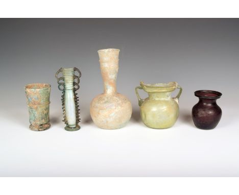 A Roman aubergine glass flask, with a waisted neck, 9.5cm high, a glass footed beaker, a glass tall flask with a pair of trip