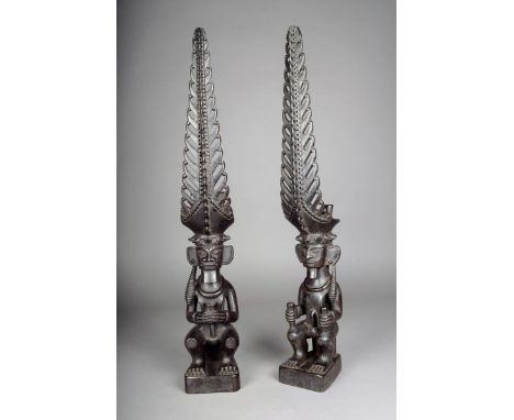 A matched pair of Nias seated ancestor figures, Indonesia, with elaborate pierced headdress, with earrings in opposing ears, 