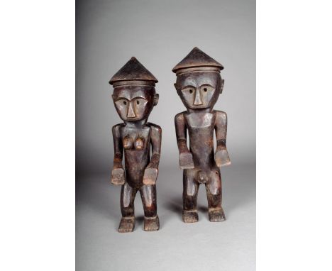 A pair of Flores standing figures, Indonesia, male and female, with conical headdresses, 39.5cm and 37cm high. (2)