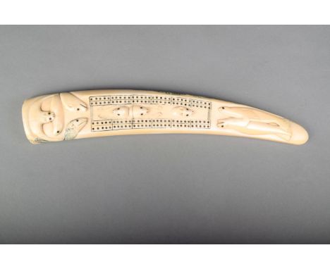 λ An Inuit walrus tusk cribbage board, the top relief carved seals, a polar bear and a serpent, the underside decorated seals