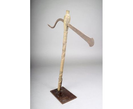 A Nguni/Shona prestige axe, South Africa, with an iron blade and intricate brass wirework bound shaft, 46cm high, on a stand.