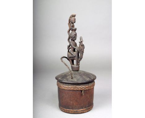 A Batak cylindrical wood container, Indonesia, with fibre binding, the cover with a carved finial with figures, a singa, serp