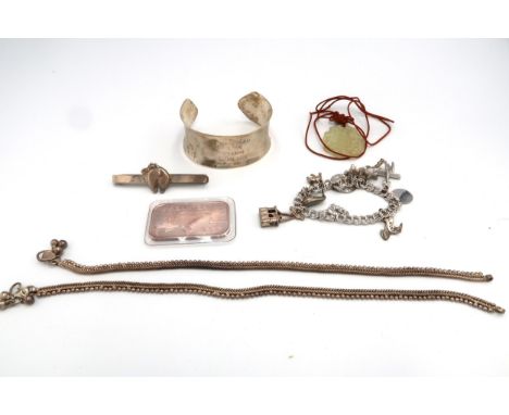 A group of silver jewellery comprising a Zambian silver bangle, a Stirling silver charm bracelet with charms, many from Alask