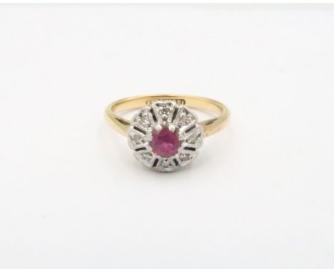 An Art Deco style ruby and diamond flower cluster ring. Size N 1/2. Stamped 18ct and plat. Weight 3.76 grams.