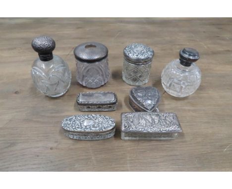 A silver heart shaped trinket box, the lid with cherubs and six silver topped dressing table gars as well as a plated example