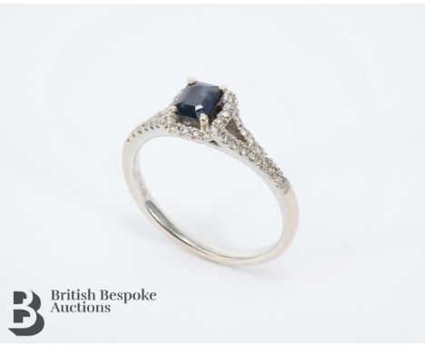 18ct white gold diamond and sapphire ring. The midnight blue sapphire measuring 5 x 4mm, halo set with 0.20cts of diamonds, S