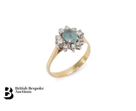 An 18ct yellow gold diamond and aquamarine ring. The ring set with an oval aquamarine measuring 6.5 x 5mm, surrounded by appr