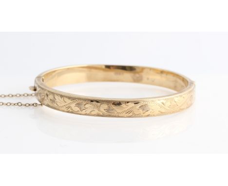 A 9ct yellow gold hinged bangle, half engraved with scrolling foliage design, hallmarked Birmingham 1972.