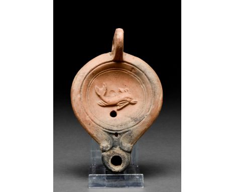 Ca. 1-200 AD A mould-made red terracotta oil lamp with a flat base, a recessed tondo with a small fill hole, and a playful do