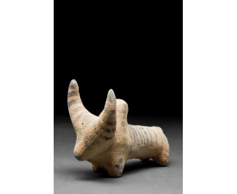 Ca. 3rd Millennium BC A creme-coloured ceramic figurine of a zebu bull with rondel eyes. Painted with stripes on the back, sh