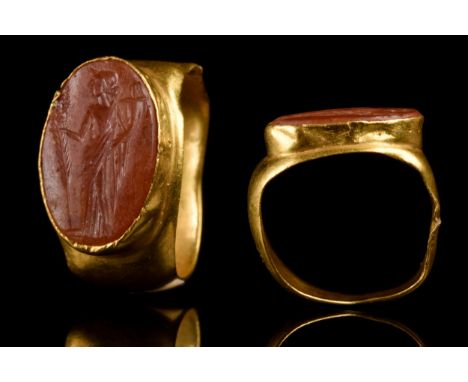 Ca. 100-300 AD A gold finger ring comprising a flat-section round hoop with expanding shoulders to support a large oval carne