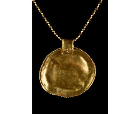 Ca. 100-300 AD A finely rendered gold disc-shaped pendant, hammered from thin gold with ropework decoration on the edge. A ri