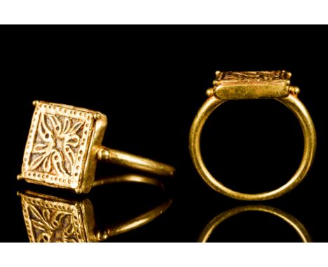 Ca. 1200-1400 AD A gold finger ring of a round-section hoop and an applied square-shaped bezel flanked by a pair of fine gran