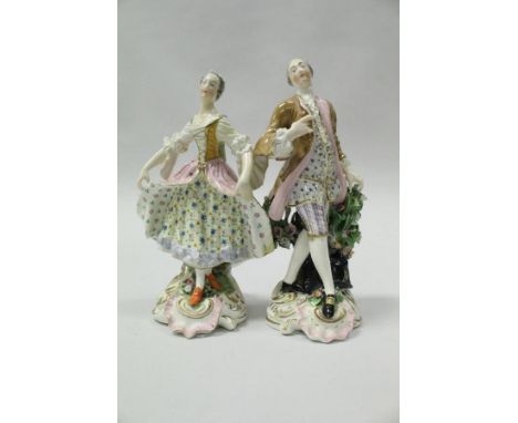 A pair of 19th Century Meissen figures of a lady and gentleman in 18th Century dress, raised on floral decorated stump and sc