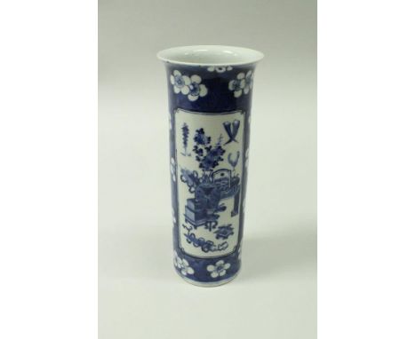 A Chinese blue and white cylinder vase with flared rim decorated with panels of household items on a prunus blossom decorated