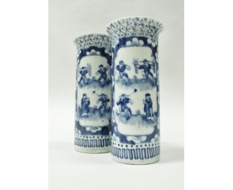 A pair of Chinese blue and white cylinder vases, each decorated with panels of figures on a prunus blossom ground, raised on 